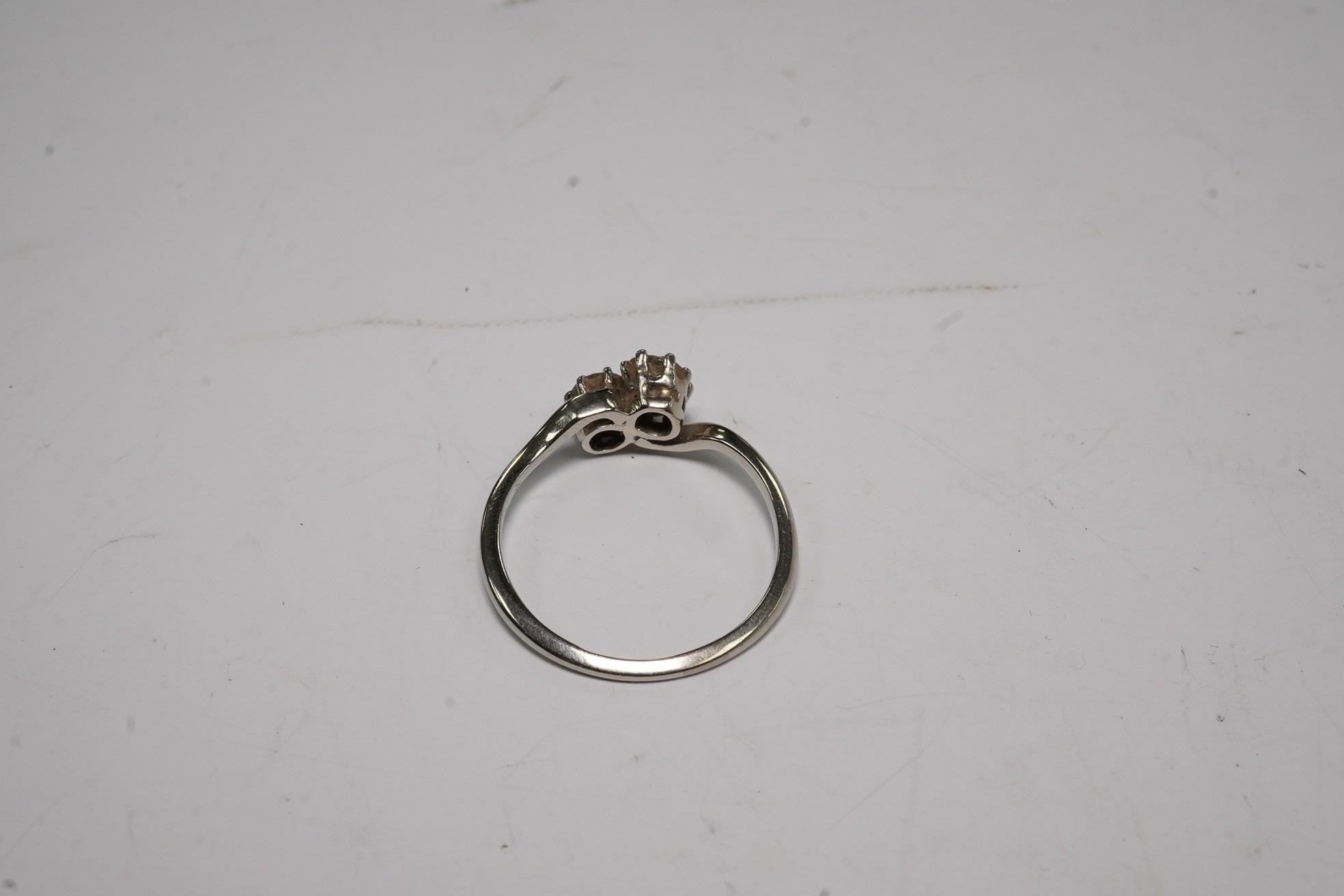 An 18ct, plat and two stone diamond set crossover ring, size O, gross weight 2.3 grams, Condition - fair to good